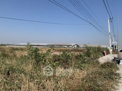 Expansive industrial land with potential for development, featuring clear skies and strategic location.