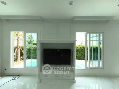 Spacious living room with large windows and pool view, perfect for relaxation.