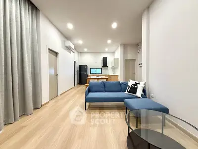 Modern open-plan living room with sleek furniture and stylish kitchen area