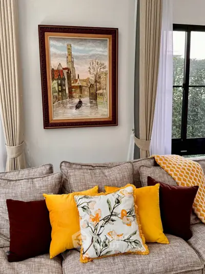 Elegant living room with cozy sofa and vibrant cushions, framed art, and large window view.
