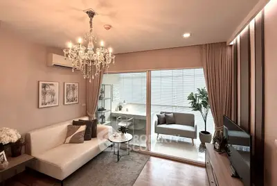 Elegant living room with chandelier and modern decor, featuring a cozy seating area and large windows.