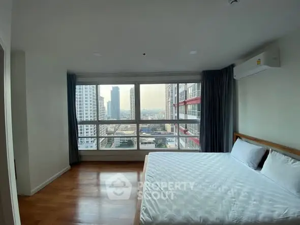 Spacious bedroom with large window offering stunning city view in modern apartment