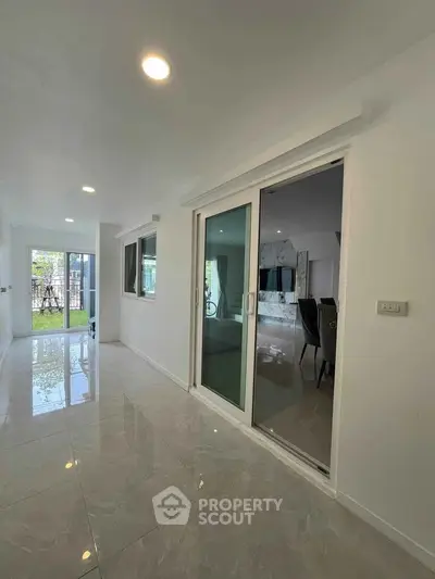 Spacious modern living area with sliding glass doors and glossy tiled floors