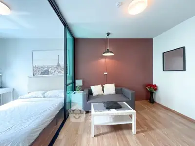 Modern studio apartment with stylish living area and cozy bedroom separated by glass partition.