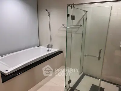 Modern bathroom with glass shower and bathtub in sleek design.