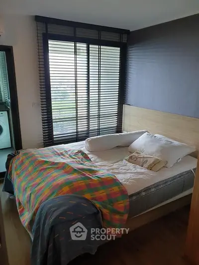Cozy bedroom with large window and modern decor, featuring a comfortable bed and vibrant blanket.