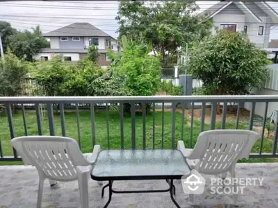 Charming garden view from a cozy balcony with seating area in a suburban home.