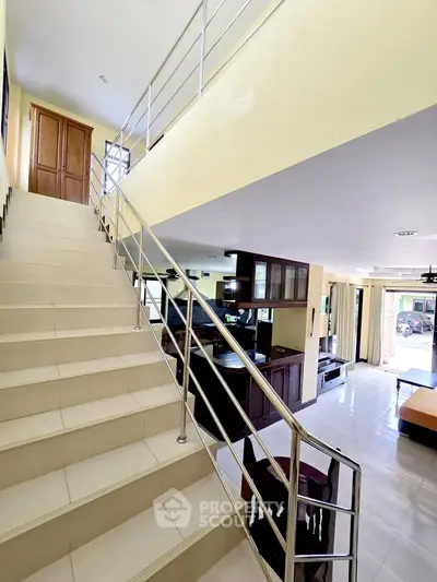 Spacious modern living room with staircase and open kitchen layout, perfect for family gatherings.