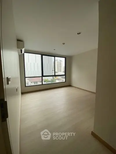 Spacious empty room with large window and city view, perfect for customization.