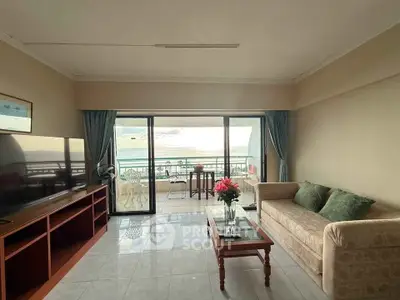 Spacious living room with ocean view balcony, elegant decor, and natural light.
