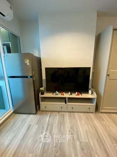 Modern living room with sleek TV setup and stainless steel fridge