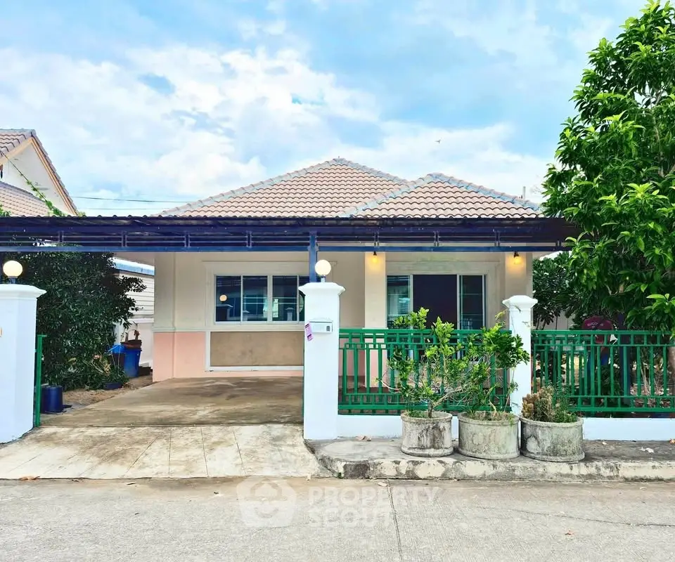 Charming single-story home with green fence and spacious driveway