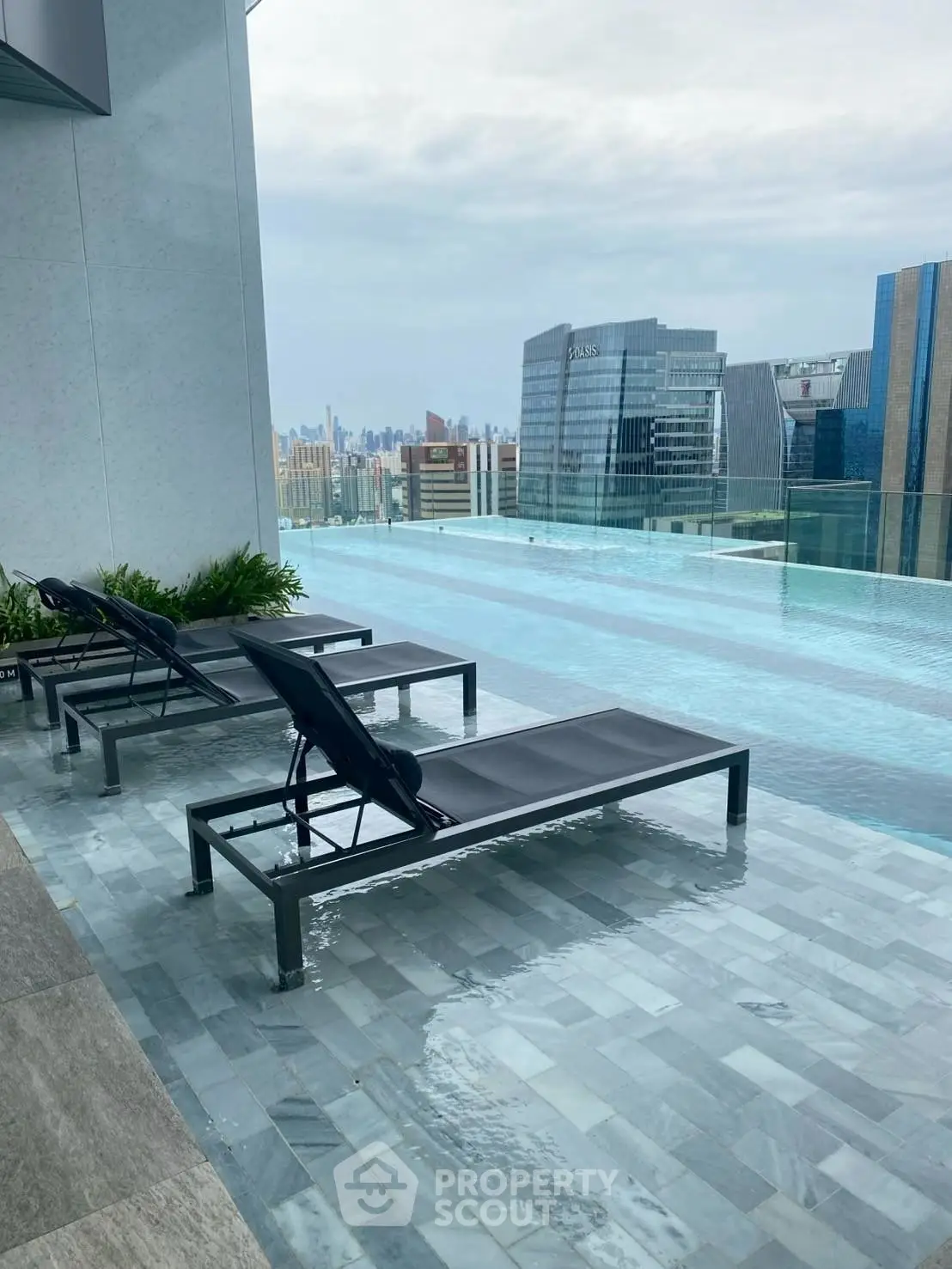 Luxurious rooftop infinity pool with stunning city skyline views and modern lounge chairs.