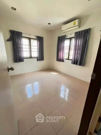 Bright empty bedroom with tiled floor and air conditioning unit
