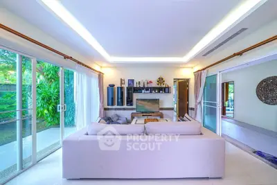 Spacious living room with modern decor and large windows overlooking lush greenery.