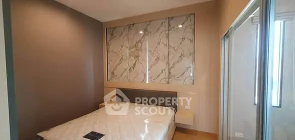 Modern bedroom with stylish marble accent wall and large window for natural light.