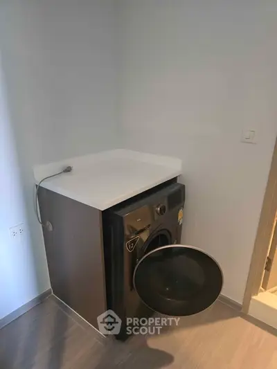 Compact laundry area with modern washing machine in sleek corner setup.
