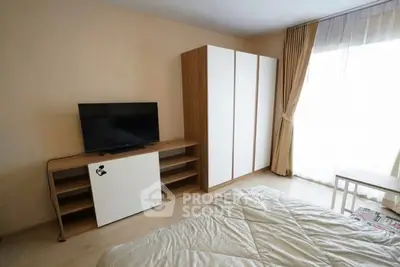 Cozy bedroom with modern TV setup and ample natural light