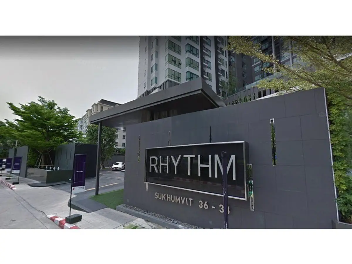 Modern condominium entrance at Rhythm Sukhumvit 36-38 with sleek design and lush greenery.
