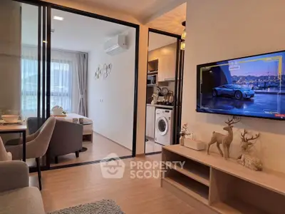 Modern living room with open kitchen and washing machine, featuring stylish decor and natural light.