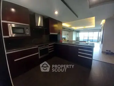 Modern kitchen with dark wood cabinets and open layout in luxury apartment