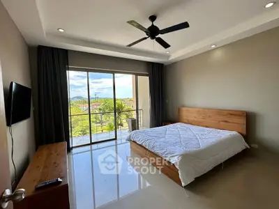Spacious bedroom with large windows and scenic view, featuring modern furnishings and ceiling fan.