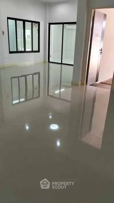 Spacious modern living room with glossy tiled floors and large windows for natural light.