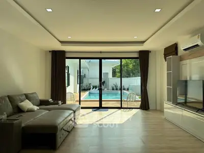 Spacious living room with pool view, modern furniture, and large glass doors for natural light.