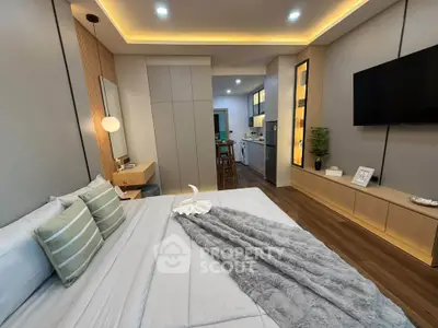 Modern bedroom with stylish decor and open layout leading to kitchen area.