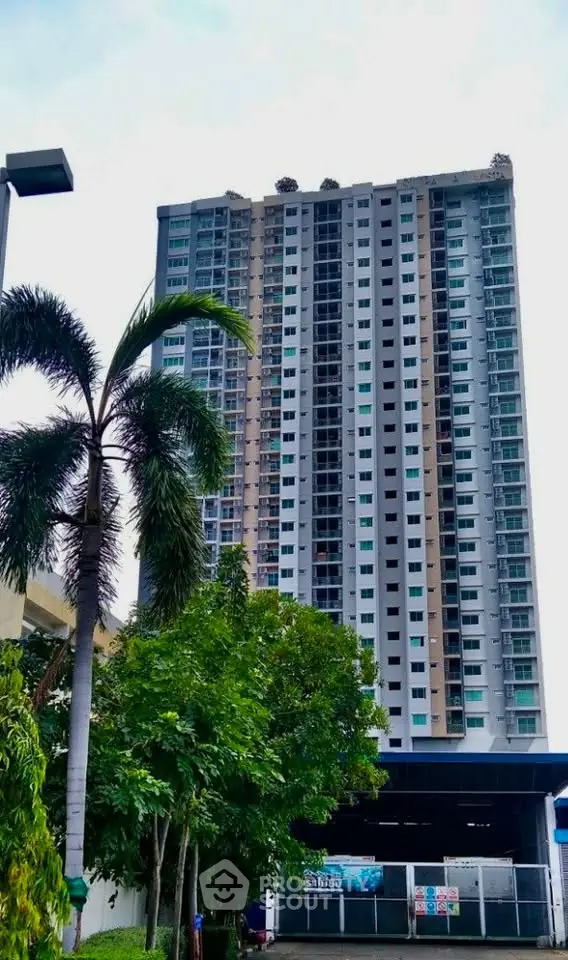 Modern high-rise residential building with lush greenery and palm tree in foreground.