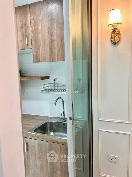Compact kitchen with wooden cabinets and modern lighting