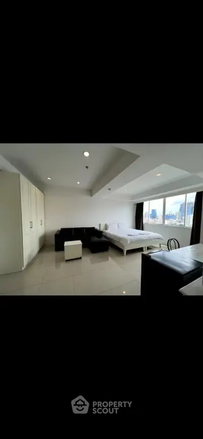 Spacious modern studio apartment with city view, featuring sleek furnishings and ample natural light.