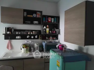Compact kitchen with modern cabinets and appliances, featuring a vibrant green fridge.
