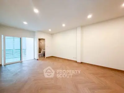 Spacious empty living room with wooden flooring and balcony access