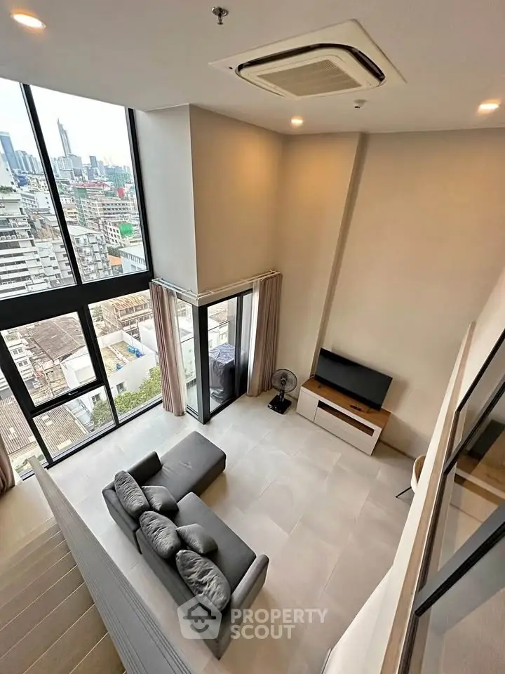 Modern loft apartment with high ceilings and city view, featuring a cozy living area and large windows.