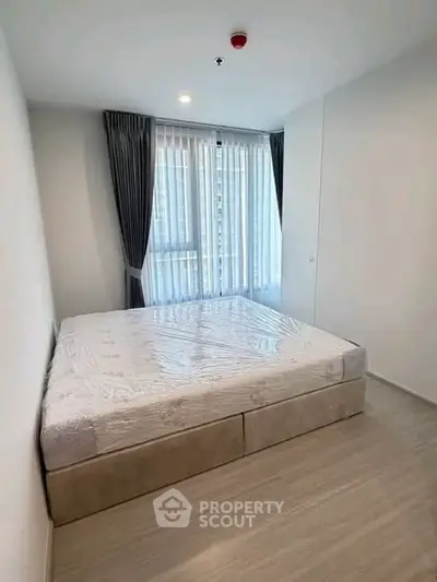 Modern bedroom with large window and elegant curtains in a stylish apartment.
