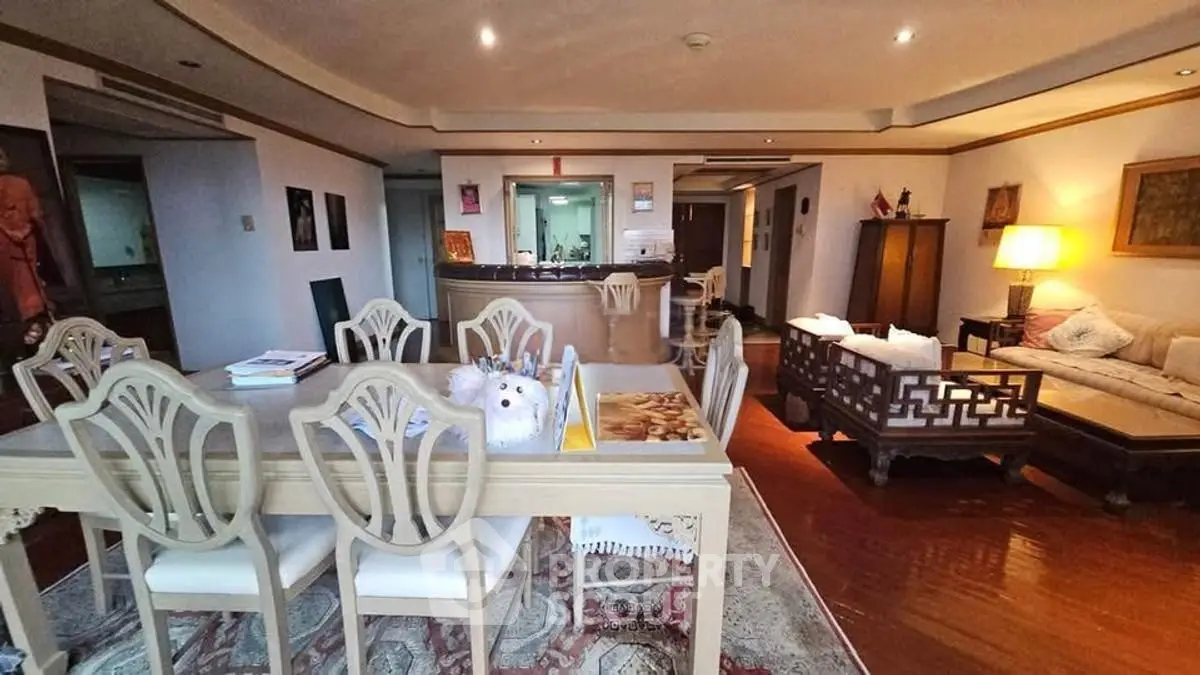 Spacious living room with elegant dining area and cozy seating, featuring classic wooden furniture and warm lighting.