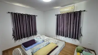 Cozy bedroom with minimalist decor, featuring a mattress on wooden flooring and air conditioning.