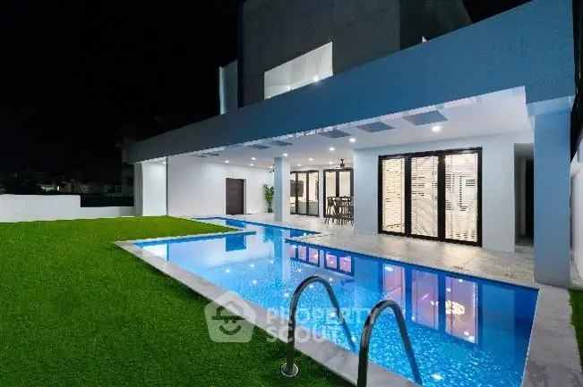 Luxurious modern home with stunning pool and elegant outdoor lighting at night.