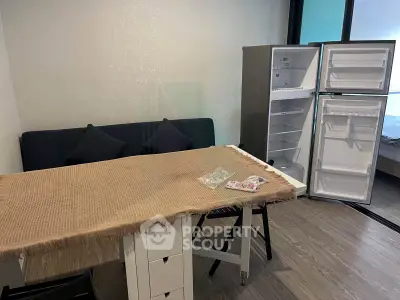 Cozy living space with sofa, table, and open fridge in modern apartment.