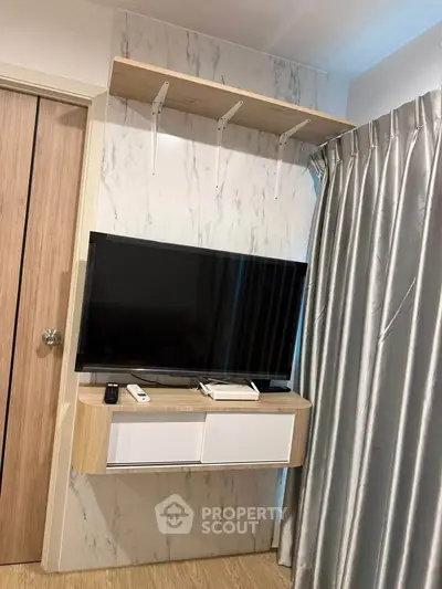 Modern living room with wall-mounted TV and stylish shelving in a cozy apartment.