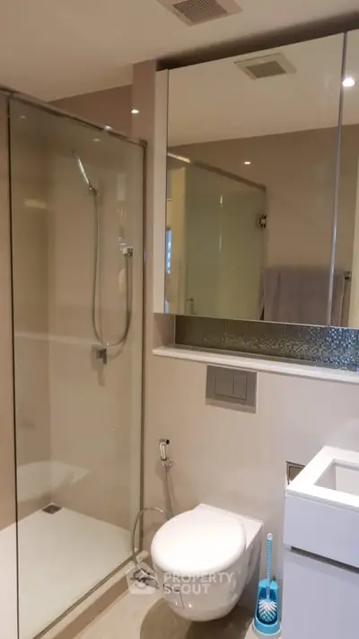Modern bathroom with glass shower and sleek fixtures in contemporary apartment.