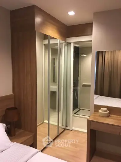 Modern bedroom with ensuite bathroom featuring glass shower and wooden accents.