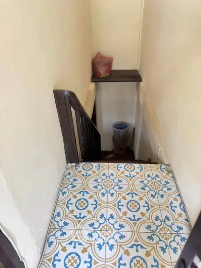 Charming staircase with vintage patterned tiles and wooden railing in cozy home.