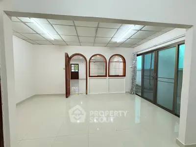 Spacious living room with large windows and modern tile flooring