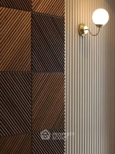 Modern interior wall with stylish wooden paneling and elegant sconce lighting.