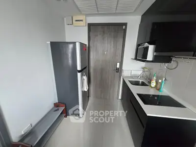 Modern kitchen with sleek black cabinets and stainless steel appliances in a compact layout.