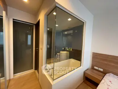 Modern apartment with unique glass-enclosed bathtub adjacent to bedroom, featuring sleek design and warm wood accents.
