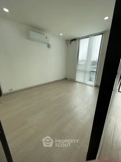 Spacious empty room with air conditioning and large windows, ideal for customization.