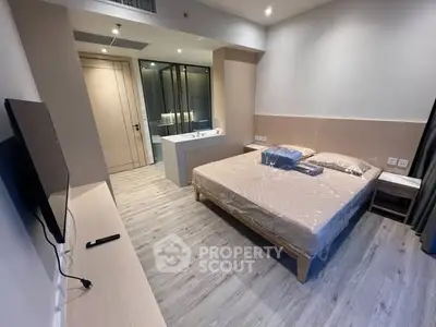 Modern bedroom with sleek design and ensuite bathroom, featuring a mounted TV and stylish flooring.